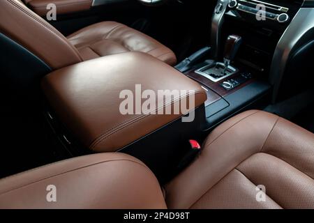 Die Armlehne im Fahrerfahrzeug ist mit Kunstleder bezogen. Schönes Leder Auto Innenarchitektur. Luxuriöse Ledersitze im Auto. Braune Ledersitzbucht Stockfoto
