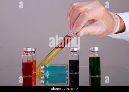 Ärzte halten Reagenzgläser mit Blut in der Hand. Arzneimittelfläschchen mit farbiger Lösung. Stockfoto