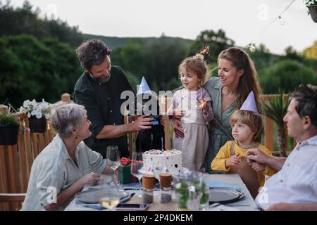 Familie mehrerer Generationen feiert den Geburtstag ihres Hundes und veranstaltet eine Gartenparty draußen auf der Terrasse. Stockfoto