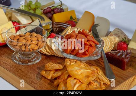 Nahaufnahme einer Gourmet-Käse- und Wurstplatte mit verschiedenen Käsesorten, Crackern, Mandeln, getrockneten Aprikosen, Trauben, Erdbeeren und Fruchtpaste. Stockfoto