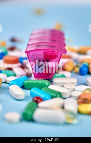 Stapeln Sie verschiedene Pillen und Tabletten mit dem Organizer. Vertikaler Shot blauer Hintergrund. Stockfoto