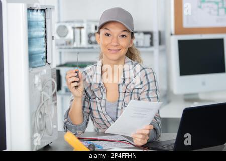 Lächelnde Frau, die Elektrogeräte repariert Stockfoto