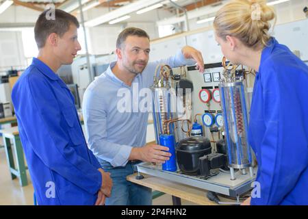 Ingenieur im Werk mit Auszubildenden, die die Komponenten prüfen Stockfoto