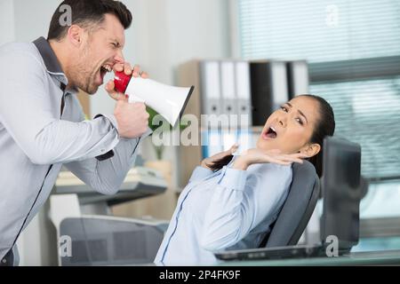Büromanager schreit durch Megafon nach entsetzlichem Mitarbeiter Stockfoto