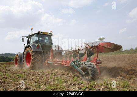 Lohnunternehmer mit Fendt-Traktor 714 und Fünffurchenpflug Kverneland, Pflügen von trockenem Boden, Cotes dArmor, Bretagne, Frankreich Stockfoto