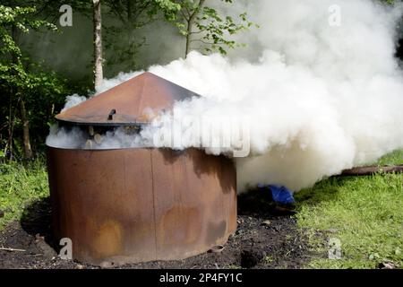 Holzkohle verbrennt, Holzscheite verbrennt, um Holzkohle zu erzeugen, von einer einheimischen Wildtiergruppe in privatem Waldland, West Yorkshire, England, Großbritannien Stockfoto