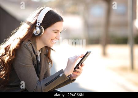 Glückliche Frau, die im Park am Telefon Audio hört Stockfoto