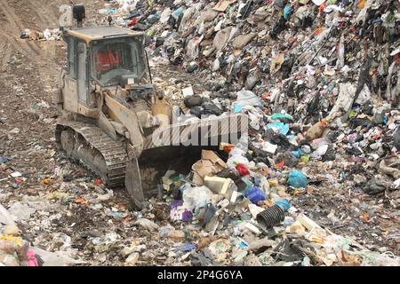 Bulldozer, der Müll auf einer Mülldeponie transportiert, Dorset, England, Großbritannien Stockfoto