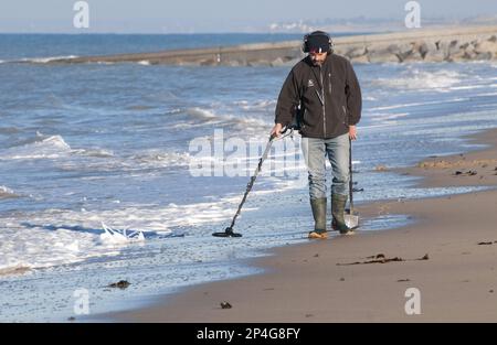 Mann, der am Strand einen Metalldetektor benutzt, in der Nähe von Granville, Manche, Normandie, Frankreich Stockfoto
