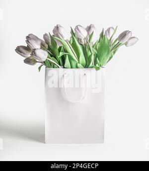 Weiße Tulpen in einer Einkaufstasche auf weißem Hintergrund mit Schatten, Vorderansicht Stockfoto