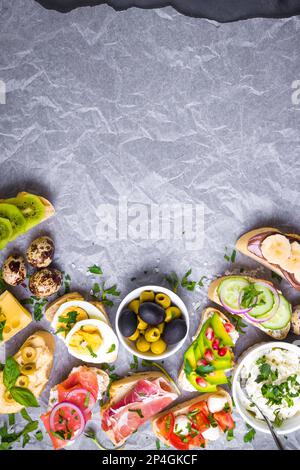 Gemischte gesunde Sandwiches im Hintergrund. Sandwich-Bar oder Buffet. Ciabatta Sandwiches mit Dips, Fisch, Käse, Fleisch, Gemüse, Obst. Platz für Stockfoto