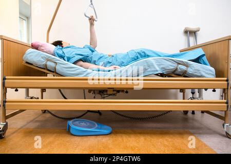 Seitenansicht des gekrümmten elektrischen Krankenhausbetts mit Haltegriff zu Hause Stockfoto