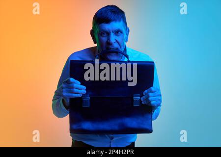 Porträt eines erwachsenen Mannes mittleren Alters, der sich emotional mit Aktentasche über abgestuftem blauem orangefarbenen Hintergrund in Neonlicht posiert. Konzept der Emotionen und Stockfoto
