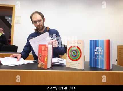 Augsburg, Deutschland. 06. März 2023. Ein 34-jähriger Mann sitzt hinter Büchern, die sich mit dem Klimawandel befassen, auf dem Dock am Bezirksgericht. Der Mann wird beschuldigt, die Regierung Schwabiens im Oktober 2022 trotz eines Verbots mit zwei anderen Personen besetzt zu haben und den damaligen Präsidenten der Regierung der Korruption beschuldigt zu haben. Kredit: Karl-Josef Hildenbrand/dpa/Alamy Live News Stockfoto