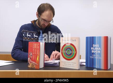 Augsburg, Deutschland. 06. März 2023. Ein 34-jähriger Mann sitzt hinter Büchern, die sich mit dem Klimawandel befassen, auf dem Dock am Bezirksgericht. Der Mann wird beschuldigt, die Regierung Schwabiens im Oktober 2022 trotz Hausverbot mit zwei anderen Personen besetzt zu haben und den damaligen Regierungspräsidenten der Korruption beschuldigt zu haben. Kredit: Karl-Josef Hildenbrand/dpa/Alamy Live News Stockfoto