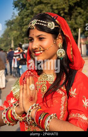 Indien, Rajasthan, Bikaner, Kamelfestivalparade, wunderschöne Rajasthani-Frau in rotem Sari, die Namaste-Geste macht Stockfoto