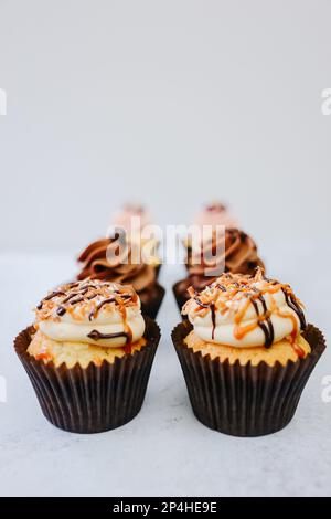 Maßgeschneiderte Cupcakes mit dickem Zuckerguss und karamellfarbenem Schokoladenregen Stockfoto