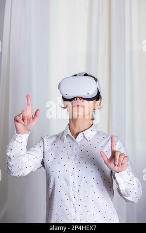 Eine junge Frau, die mit einer VR-Brille auf etwas zeigt. Stockfoto