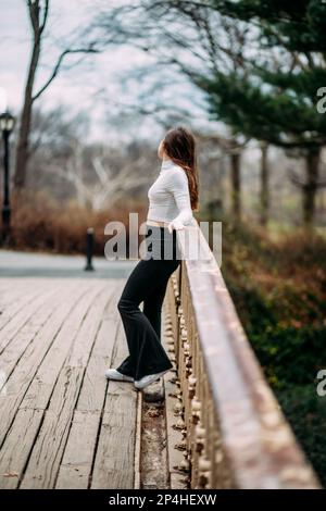 Ein Mädchen, das auf der Brücke steht und wegschaut Stockfoto