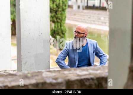 Ein bärtiger Mann, der in einem Park sitzt und sich entspannt Stockfoto