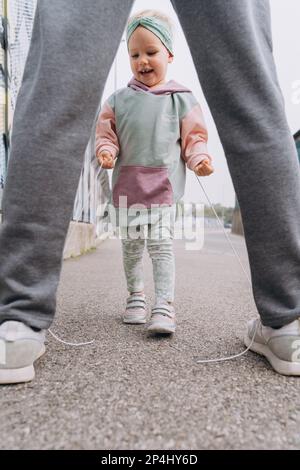 Ein stilvolles Mädchen im Hoodie-Hooligan löst Dads Schnürsenkel Stockfoto