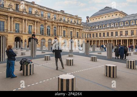 Touristen steigen auf die Colonnes de Buren im Palais Royal im 1. Arrondissement, Paris. Stockfoto