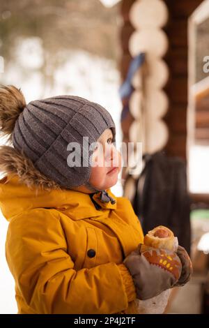 2 Jahre alter Junge, der Hot Dog im Freien isst Stockfoto