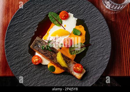 Gegrilltes Lachssteak mit Sauce auf einem Teller auf einem Holztisch Stockfoto