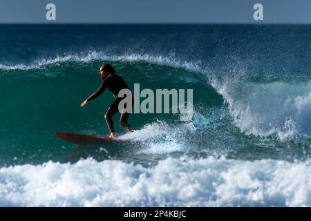 Spektakuläre Surfaktion als männlicher Surfer reitet auf einer Welle im Fistral in Newquay in Cornwall in England in Großbritannien. Stockfoto