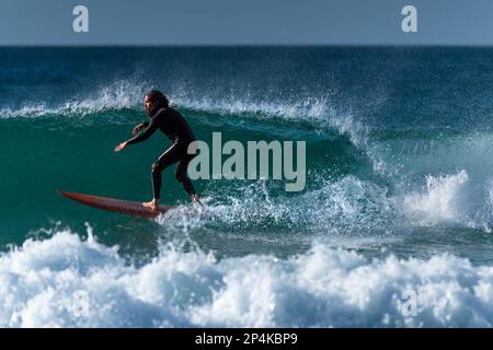 Spektakuläre Surfaktion als männlicher Surfer reitet auf einer Welle im Fistral in Newquay in Cornwall in England in Großbritannien. Stockfoto