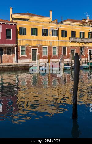 Farbenfrohe Gebäude, die sich im Februar in Murano, Venedig, Italien, im Kanalwasser widerspiegeln Stockfoto