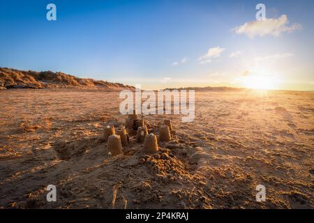 Sandburg am wunderschönen Brancaster Beach in Norfolk bei Sonnenuntergang mit blauem Himmel und hellen Wolken Stockfoto