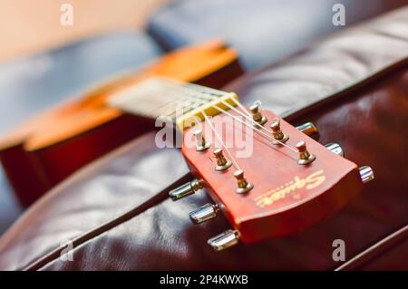 Eine Nahaufnahme eines klassischen Gitarrenkopfs, der auf einer Couch liegt. Stockfoto