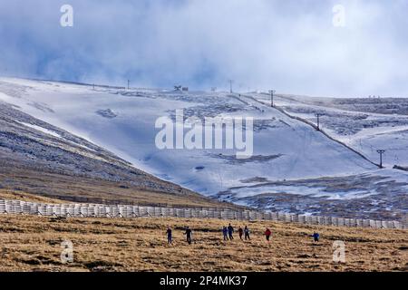 Fort William Aonach Mor Mountain Nevis ist eine Gruppe von acht Wanderern, die von schneebedeckten Skipisten absteigen Stockfoto