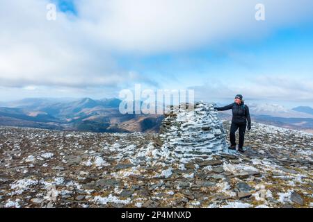 Ein Geher am Gipfelkairn auf dem Gipfel des schottischen Munro-Berges von Moruisg Stockfoto