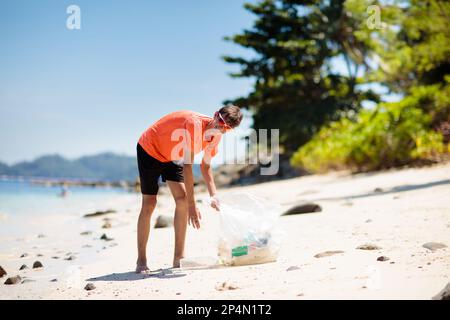 Plastikmüll. Meer- und Meeresverschmutzung. Strand aufräumen. Junger Mann, der benutzte Plastikflaschen am Sandstrand pflückt. Umweltaktivistin Stockfoto