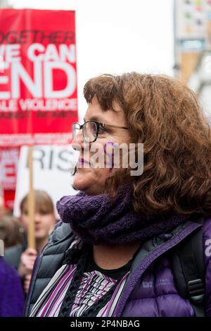 Frau mit lila Frauenzeichen auf dem Gesicht, "Million Women Rise" jährlicher märz gegen Gewalt gegen Frauen, London, UK 04/03/2023 Stockfoto