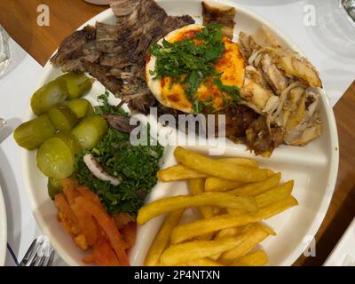 Blick von oben auf einen Teller mit Schawarma, serviert auf einem weißen Teller und auf einem Holztisch. Arabische oder nahöstliche Küche. Stockfoto