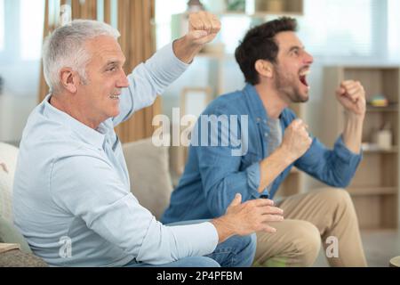 Aufgeregter Mann und Vater auf der Couch beim Fußballspiel Stockfoto