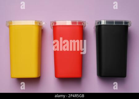Kanülenbehälter für gebrauchte Spritzen auf violettem Hintergrund, flach liegend Stockfoto