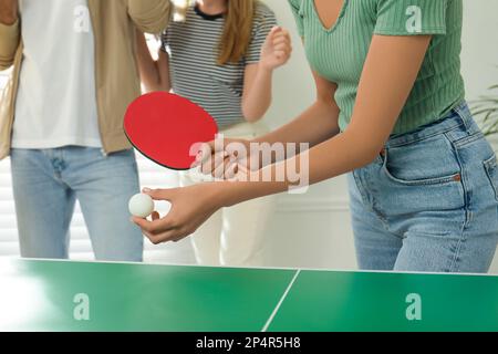 Eine Frau, die Tischtennis mit Freunden drinnen spielt, Nahaufnahme Stockfoto