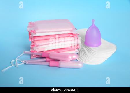 Menstruationseinlagen und andere Hygieneprodukte auf hellblauem Hintergrund Stockfoto