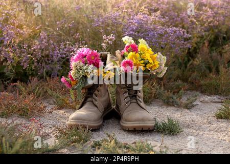 Stiefel mit wunderschönen Wildblumen auf der Wiese Stockfoto