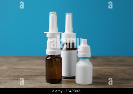 Nasensprays in verschiedenen Flaschen auf Holztisch vor hellblauem Hintergrund Stockfoto