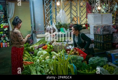 Eine kambodschanische Frau kauft Gemüse von einem Bauernhalter auf dem Central Market in Phnom Penh, Kambodscha. Stockfoto