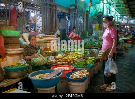 Eine kambodschanische Frau kauft Gemüse von einem Bauernhalter auf dem Central Market in Phnom Penh, Kambodscha. Stockfoto