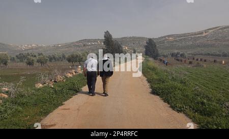 TURMUS AYYA, ISRAEL - MÄRZ 5: Palästinensische Männer gehen am Rande der palästinensischen Stadt Turmus Ayya in der Nähe der israelischen Siedlung Shilo im Ramallah- und al-Bireh-Gouvernement am 5. März 2023 im Westjordanland, Israel. Israel hatte der Regierung Biden mitgeteilt, dass es die Legalisierung weiterer Außenposten im Westjordanland mehrere Monate lang hinauszögern würde. Aber dass es mit der Legalisierung der neun Außenposten im Westjordanland und der Genehmigung, Hunderte von Wohneinheiten in verschiedenen Teilen Judäas und Samarias zu bauen, immer noch vorankommen würde. Stockfoto