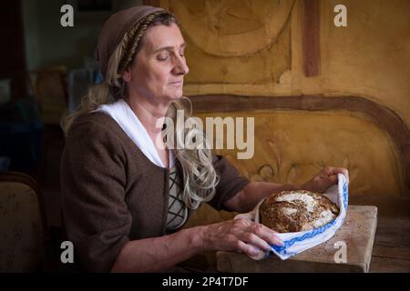 Eine Frau in authentischem Bauernrenaissance-Kostüm mit Brot. Stockfoto