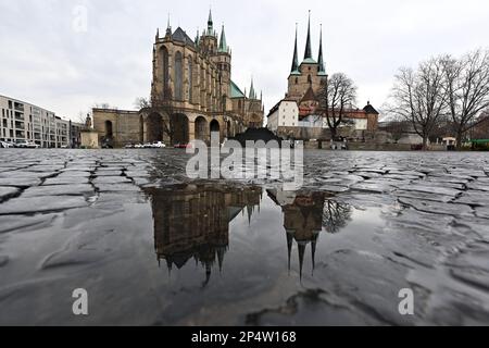 Erfurt, Deutschland. 06. März 2023. Die katholische Kathedrale von St. Maria und die Kirche St. Severus spiegelt sich auf dem nassen Bürgersteig des Kathedralenplatzes wider. Vom 29. Mai bis 2. Juni 2024 findet in der Hauptstadt Thüringen der 103. Deutsche katholische Tag statt. Kredit: Martin Schutt/dpa/Alamy Live News Stockfoto