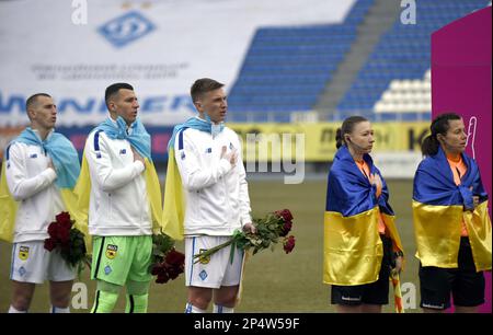 KIEW, UKRAINE - 4. MÄRZ 2023 - Spieler des FC Dynamo Kyiv und Schiedsrichter, die in ukrainische Flaggen eingewickelt sind, spielen vor dem 2022-2023. Ukr die Nationalhymne Stockfoto